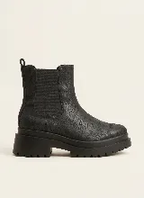 Bota estilo Chelsea de cuero con textura craquelada, cuenta con paneles elásticos laterales y suela de plataforma dentada.
