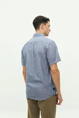 Camisa de manga corta confeccionada en una mezcla de lino y algodón, con cuello clásico, cierre frontal de botones y bolsillo en el pecho con logo bordado.