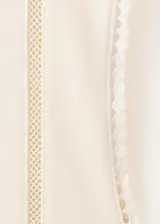 Camiseta sin mangas color beige, con cuello redondo y detalles de encaje en las costuras de los hombros y laterales.
