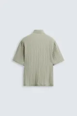 Camisa de manga corta con cuello solapa, confeccionada en tejido de mezcla de lyocell con textura de efecto arrugado y cierre frontal de botones.