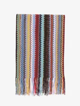 Chal tipo bufanda de tacto suave con patrón de zigzag multicolor en franjas verticales. Presenta flecos en los bordes.