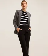 Pantalón zanahoria de vestir negro, de tiro alto, con trabillas en la cintura, cierre con botón contrastante y cremallera.