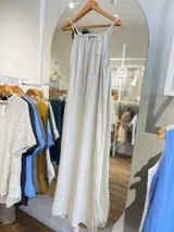 Vestido largo de lino color negro oscuro, con escote fruncido y tirantes finos ajustables. Presenta aberturas laterales en el ruedo.