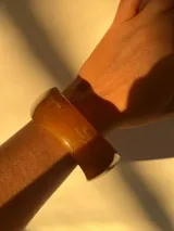 Brazalete rígido color marrón claro con forma irregular.