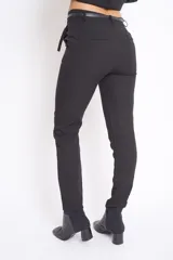Pantalón negro de vestir, de corte recto, con bolsillos laterales y traseros. Se ajusta a la cintura con cinturón de cuero negro.