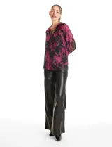 Blusa de microtul con estampado floral en tonos fucsia sobre base negra. Presenta cuello a la base con frunces, escote en V con lazo de ajuste y mangas largas con puños elastizados. Incluye forro interno a tono.