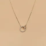 Conjunto de collar doble en plata 925 con dijes entrelazados, uno circular con circonias incrustadas y otro circular liso. Incluye aros tipo argolla pequeños con circonias.