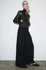 Pantalón de tiro medio con diseño de raya diplomática, corte wide leg y detalle de pinzas en el delantero. Cuenta con cintura con trabillas, bolsillos laterales y cierre frontal con cremallera, botón y ganchos metálicos.