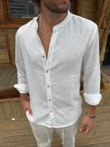 Camisa blanca de corte clásico con cuello mao, manga larga con puños abotonados y cierre frontal con botones de madera.