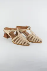Sandalias de cuero color beige estilo cangrejera con punta fina, diseño de tiras entrelazadas, tira ajustable en el tobillo con hebilla dorada y taco geométrico de madera.