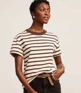 Blusa de corte boxy con mangas cortas, confeccionada en algodón. Presenta un diseño de rayas horizontales en color crema y marrón, con cuello redondo de punto en contraste.