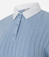 Buzo cropped de punto con textura trenzada, color celeste, con cuello polo camisero en contraste color blanco y cierre frontal con botones. Presenta mangas largas con puños acanalados y ruedo también acanalado.