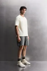 Camiseta de corte regular fit confeccionada en algodón, con cuello redondo y manga corta. Presenta un estampado frontal con el texto 'ATHLETICZ TRAINING CREW' con efecto desgastado.