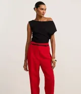 Pantalón de sastrería corte carrot, color beige, con cintura alta, pinzas frontales y cinturón fino incorporado con hebilla metálica.