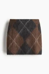 Pollera corta de punto con diseño argyle en tonos marrón y negro. El tejido es afelpado y presenta un patrón de rombos con líneas diagonales más claras.