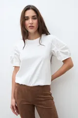 Remera negra de algodón con cuello redondo y mangas cortas abullonadas con detalle de frunces.