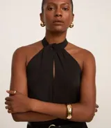 Blusa negra sin mangas confeccionada en chiffon, con cuello halter y abertura en forma de gota en el escote.