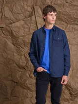 Overshirt de textura jaspeada en tonos azul oscuro con pequeñas motas de colores, de manga larga, con cuello camisero, cierre frontal de botones y un bolsillo en el pecho.