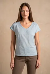 Remera celeste de algodón con cuello en V, mangas cortas y diseño bordado de flores estilo broderie distribuidas en el frente y hombros.