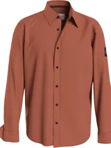 Camisa color ladrillo de corte relaxed, confeccionada en sarga de algodón elástico. Tiene cuello en punta, cierre de botones, puños redondos y bajo recto.