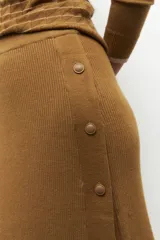 Falda larga marrón de punto con elástico en la cintura y botones decorativos en un lateral.