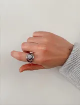 Anillo de acero quirúrgico con diseño circular abierto y piedra central redonda de color negro.