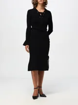 Falda midi negra de tejido de punto acanalado, con silueta ajustada, bajo acampanado y detalle de lazos entrecruzados en el lateral.