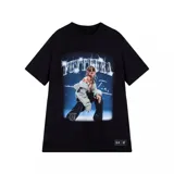 Remera negra de manga corta con cuello redondo, parte de una colaboración entre Under Armour y Tini. Presenta un estampado grande en el centro con la palabra "FUTTTURA" en tipografía plateada brillante y una imagen de Tini Stoessel en un ambiente oscuro y estrellado.