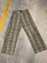 Pantalón de corte super baggy con estampado de piel de serpiente en tonos grises y beige.