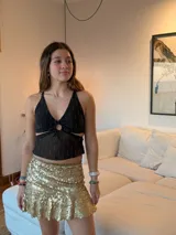 Pollera corta con volado en el ruedo, confeccionada en tela con lentejuelas doradas.