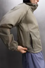 Chaqueta cortavientos de tejido técnico con estructura ripstop, cuello subido con capucha, cierre frontal de cremallera, bolsillos laterales ocultos y zonas perforadas para mayor transpirabilidad.