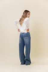 Jean de corte wide leg y tiro alto, confeccionado en denim rígido con un ligero efecto de desgaste. Presenta un diseño de calce relajado con pernera amplia, cintura marcada, bolsillos clásicos y cierre frontal con botón metálico.