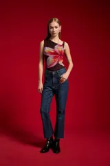 Pantalón de jean azul oscuro, de tiro medio y corte flare, con diseño de bolsillos clásicos y terminación desmechada en las pantorrillas.