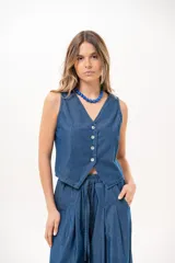 Chaleco de denim azul sin mangas, con escote en V y cierre frontal de cuatro botones.