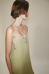 Vestido midi confeccionado en hilatura de viscosa, de color verde con detalles de encaje a contraste en el escote y el bajo. Cuenta con escote recto y tirantes finos ajustables.