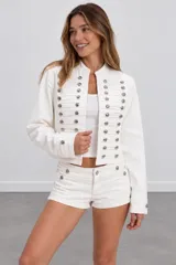 Chaqueta blanca de denim con diseño estilo militar, cuello mao y múltiples botones metálicos frontales.