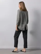 Camisa gris de tencel con cuello con solapa, escote en V y abertura central con botones. Largo de manga regulable con presilla y botón. Ruedo en espalda con tajo.