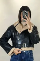 Campera tipo aviador de cuero sintético marrón con interior y detalles de corderito beige. Presenta cierre frontal cruzado, cuello solapa amplio, puños con corderito y cinturón ajustable en la cintura con hebilla metálica.