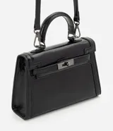 Cartera bandolera Satinato pequeña, de estructura rígida y diseño rectangular, confeccionada en PU negro con acabado levemente brillante. Cuenta con cierre frontal metálico con traba, asa de mano superior y correa larga removible y ajustable.