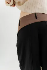 Pantalón blanco de lino y algodón, de tiro medio, con pinzas frontales, pretina ancha en la espalda con cambio de color y vivo en contratono, cortes en la mitad de la pierna de la espalda, cierre frontal con cierre y botón, y bolsillos delanteros.