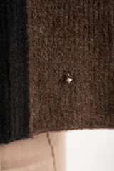 Sweater de tejido de punto grueso, con diseño de rayas verticales anchas en tonos marrón oscuro y negro. Presenta cuello redondo y mangas largas.