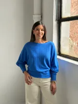 Sweater de punto color azul vibrante, con diseño de textura acanalada vertical en el frente, cuello redondo y mangas murciélago con puños ajustados.