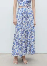 Falda larga con estampado floral en tonos azules y blancos, detalle de pliegues y cierre lateral con cremallera.