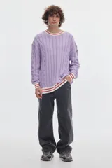 Buzo de punto blanco crudo con tejido de ochos y diseño regular. Cuenta con cuello redondo, puños y ruedo acanalados en color negro con líneas blancas en contraste.