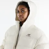 Campera puffer acolchada de color blanco marfil con capucha, cierre frontal completo y bolsillos laterales. Cuenta con el logotipo de New Balance bordado en el pecho.