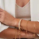 Esclava de alambre redondo en oro 9k, de diseño minimalista, con una medalla colgante que presenta un diseño grabado en forma de estrella con una circonia incrustada.