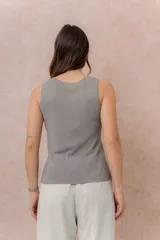 Musculosa de tejido fino con textura acanalada, color blanco, escote redondo y hombros anchos.