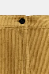 Pantalón de tiro medio confeccionado en tejido de pana, con diseño de pierna ancha, bolsillos delanteros y traseros, y cierre frontal con cremallera y botón.