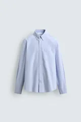 Camisa de corte regular fit confeccionada en tejido de algodón tipo Oxford. Presenta cuello abotonado, manga larga con puños abotonados, bolsillo frontal en el pecho y cierre de botonadura central.