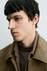 Cazadora regular fit color verde militar, confeccionada en tejido efecto ante. Presenta cuello solapa, manga larga, bolsillos de vivo en la cadera y cierre frontal de botonadura.